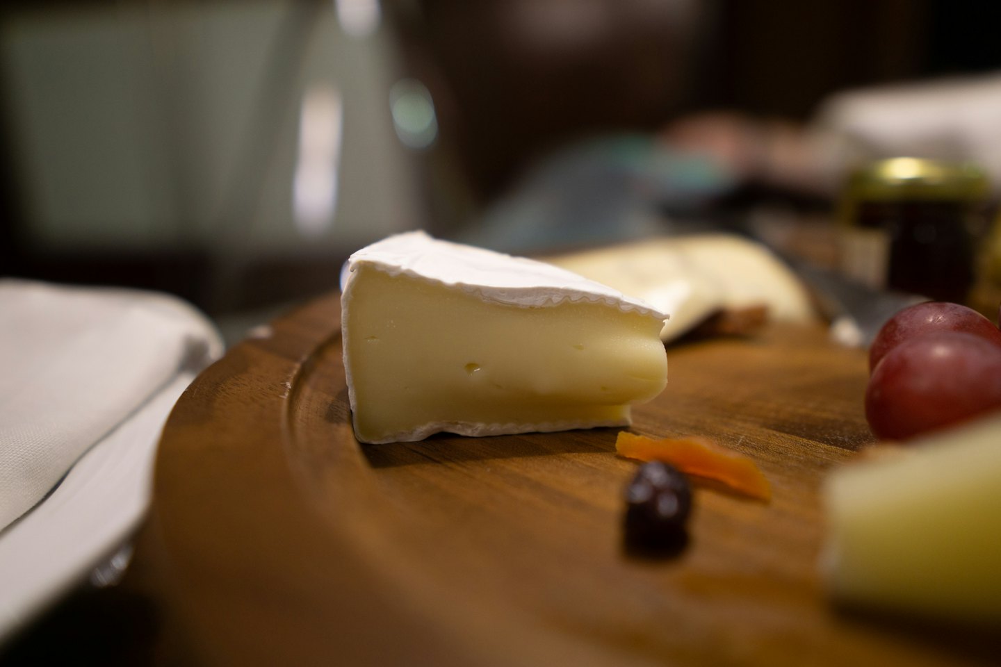 Una fetta di brie servita con uva e albicocche.